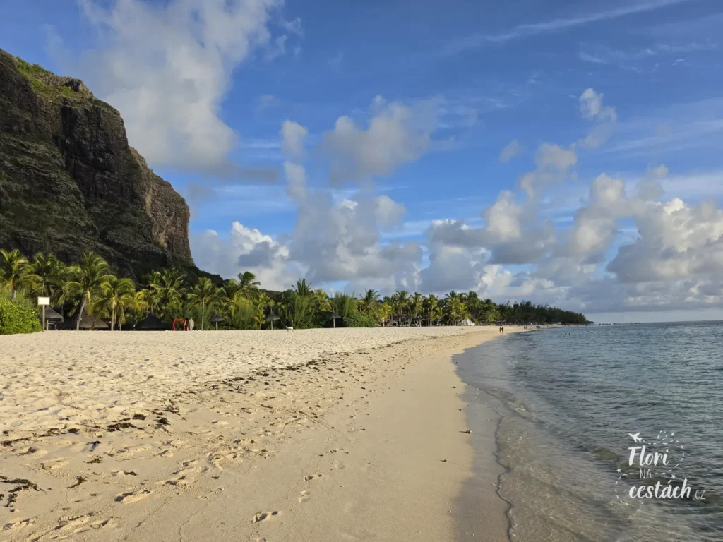 Bílá písečná pláž Le Morne beach na Mauriciu s palmami, průzračným mořem a majestátní horou Le Morne Brabant v pozadí